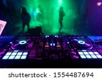 DJ mixer in the booth on the background of the dance floor with dancing people
