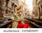 Venice, Italy travel conception: elegant traveler woman wearing hat on Gondola ride along beautiful street. Rear, back view. Tourism, vacation, lifestyle conception. Copy, empty space for text