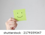 Small photo of Woman hands holding green smile face paper, good feedback rating,think positive, customer review, assessment, world mental health day, Compliment Day.