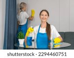 Staff of the cleaning service with professional equipment is engaged in cleaning the house, hygiene. Young woman in uniform wipes the table with a cleaning agent, microfiber cloths.