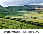 Peak District landscape and agricultural land with background views of Mam Tor mountain range and disused buildings at Castleton.