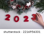 Inscription 2023 from gingerbread cookie, child hand taking cookie. New Year and Christmas decor.