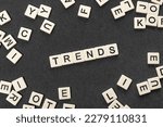 White cubes make up the words TRENDS surrounded by chaotic alphabet letters on gray background. Popular and relevant topics. Monitoring new business opportunities