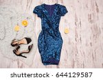 Blue dress in sequins, black shoes and halves of orange. Wooden background, fashionable concept