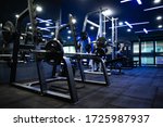 Modern gym Sports equipment in the gym Barbells of different weight on the RACK And a machine for building muscles, with blue lights interiors, gym flooring with cushioning sheets. Focusing shooting t