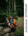Small photo of A diverse couple, their backpacks suggesting a day of exploration, relaxes on a wooden log, cherishing the memories made during their outdoor escapade