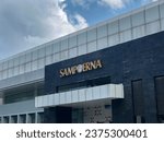 Small photo of ACEH, INDONESIA - JULY 02, 2023 : front view of PT HM Sampoerna Tbk. office exterior. with black and gray paint and cloudy sky as background