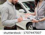 Automotive business, car sale or rental concept : Happy customer with car dealer agent making deal and signing on agreement document contract in auto showroom or car dealer office.