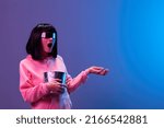 Small photo of Shocked confused brunet woman in pink hoodie trendy specular sunglasses with popcorn spread hand posing isolated in blue violet color light background. Neon party Cinema concept. Copy space