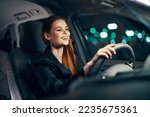 a happy, relaxed woman enjoys a night drive while sitting in a car