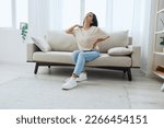 Small photo of Woman sitting on sofa at home back and lower back pain, protrusion, back problems after 30 years