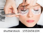 Eyelash extension procedure. Master tweezers fake long lashes beautiful female eyes.