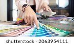 Small photo of Banner hand of woman decorator, interior and graphic designer, architect is choosing catalogue colors ral for web project.