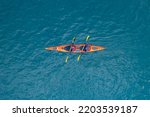 Red kayak boat two rowers on blue turquoise water sea, sunny day. Concept extreme sport, aerial top view.