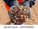 Worker engineer hold gravel in hand, checks quality at sand quarry. Industrial construction site concept.