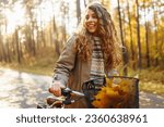 Small photo of Happy active woman in stylish clothes rides a bicycle in an autumn park at sunset. Outdoor portrait. Beautiful woman enjoying nature. Active lifestyle.