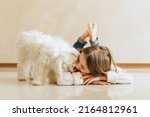 girl 9 years old with long hair model with a pet dog Maltese schoolgirl at home lifestyle on a beige background allergy veterinarian