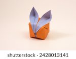 Small photo of Slightly angled view of single small origami bunny against a white backdrop. Bunny is tilted slightly to the side as if curious, sad or lonely by itself.