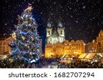 Beautiful view to the old town square of Prague during night time with a Christmas market in winter time with snow falling, Czech Republic
