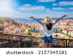 A happy tourist woman overlooks the colorful old town Alfama of Lisbon city, Portugal, and castle Sao Jorge on her sightseeing trip