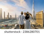 A elegant tourist couple on vacation time stands on a balcony and enjoys the sunrise view of the Dubai city skyline, UAE
