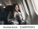 beautiful young asian woman sits in a plane and looking outside