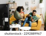 Small photo of Multiethnic couple playing videogames on sofa