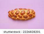Small photo of Directly above view with a homemade challah bread minimalist on a purple table. Braided bread, a traditional Jewish recipe, on a vibrant-colored background