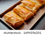 Baked puff pastry with toppings. Puffs with cheese on a wooden tray.