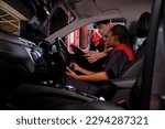 Young Black woman automotive mechanic technician and partner checking maintenance list with tablet in car interior at garage. Vehicle service fix and repair works, industrial occupation business jobs.