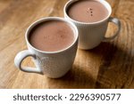 Small photo of White mugs filled with rich, steaming cocoa on a rustic wooden table. The cozy and warm ambiance, coupled with the visual appeal of the white mugs and wooden texture, visual for coffee shops or cafes