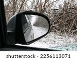 Side mirror of a car.Traveling by car in winter.View from the car.Snowy weather.Bad weather conditions.Off-road.Problems on the road.Automotive .