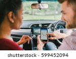 Multiethnic diverse lover couple using navigation system on smartphone in car. Mobile phone application, crowdsourced taxi or ride hailing app service, modern gadget or family travel lifestyle concept