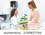 Small photo of Gynecologist preparing for an examination procedure for a pregnant woman sitting on a gynecological chair in the office