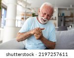 Small photo of Elderly man has pain in fingers and hands. Old man with finger pain, Man massaging his arthritic hand and wrist.
