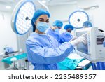 Small photo of Anesthesiologist keeping track of vital functions of the body during cardiac surgery. Surgeon looking at medical monitor during surgery. Doctor checking monitor for patient health status.