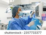 Small photo of Anesthesiologist checking monitors while sedating patient before surgical procedure in hospital operating room. Young adult female patient is asleep on operating table during surgery.
