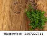 Small photo of Parsley Bunch on Old Wooden Texture Background. Cilantro Leaves, Raw Garden Parsley Twigs, Chervil Sprigs, Corriender Leaves on Dark Brown Wood Grain Table Desk Top View