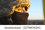 Small photo of Gaze of male ukrainian army soldier in helmet and balaclava outdoor. Profile view of young military man looking with hope at sunset. Invasion resistance. War between Russia and Ukraine. Close up.