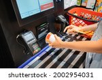 A woman reads the bar code of instant noodles soup at the self-service checkout machine in supermarket