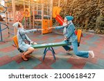 Small photo of Two childish happy woman friends or teenage girl having fun on seesaw on a playground. Concept of psychology of the new generation and relations