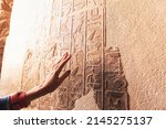 Small photo of An Egyptologist or archaeologist reads and translates Egyptian hieroglyphs carved in stone
