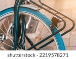 Detailed view of a retro vintage bicycle used for town transportation with blue tyre and iron trunk and flashlight