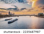 Small photo of Cityscape view of the city of Koln, the Rhine River, bridges and various barges and ships during majestic sunset.