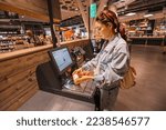 Small photo of 30 July 2022, Cologne, Germany: girl customer scanns and pays for bottle of juce at an automated self-service checkout terminal in Rewe supermarket