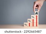 Small photo of Real estate property investment concept. Asset management, Interest rates, inflation, loan mortgage, increase tax. Hand holding house icon on wooden cube from stack block with percent and rise arrow.