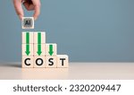 Small photo of Lean or Cost reduction by Machine learning. AI or Artifice intelligence to optimize manufacturing. Decreasing expense to maximize profits. Hand put wooden cube with AI icon and cost down green arrows.