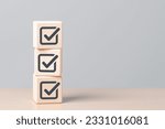 Check mark icons for jobs list on the face of wooden stacked blocks. Task lists, Checklist, Survey, Assessment, List, Confirm items, Double check, Quality Control. Goals achievement business success. 