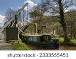 A narrowboat passes through the lift bridge at Talybont-on-Usk on the Monmouthshire and Brecon Canal, Brecon Beacons, Wales.