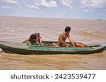 Small photo of Siem Reap,Camboda,July 6, 2019-A young boy,girl and their father eke out a living by getting tips from tourists along with their pet python on the Tonle Sap lake near Siem Reap,Cambodia